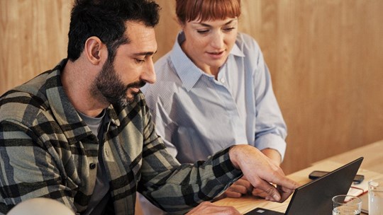 Young man and woman meeting and working on laptop discussing work