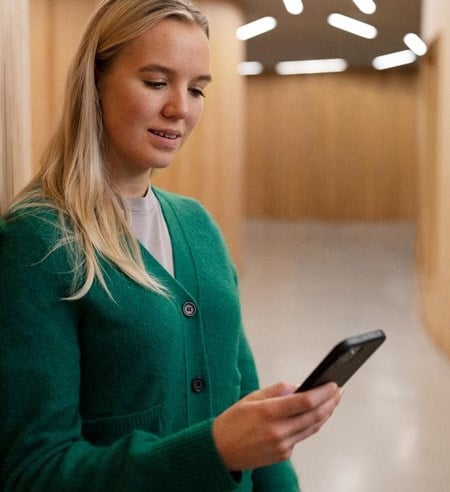 Young woman using her phone in public space smiling